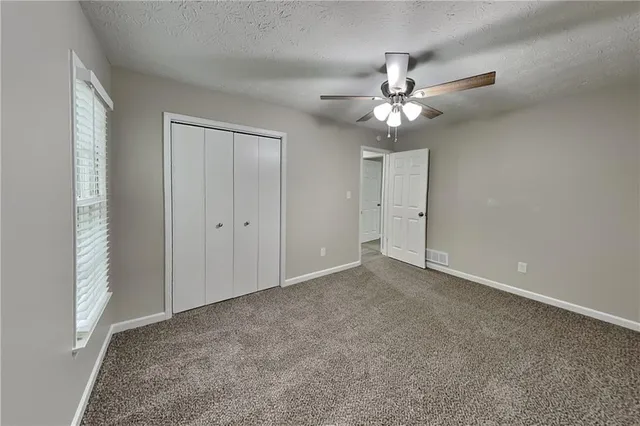 an empty room with closet and a chandelier fan