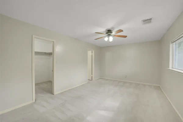 an empty room with fan and windows