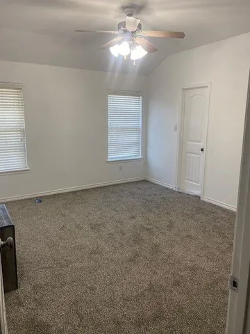 an empty room with windows and fan