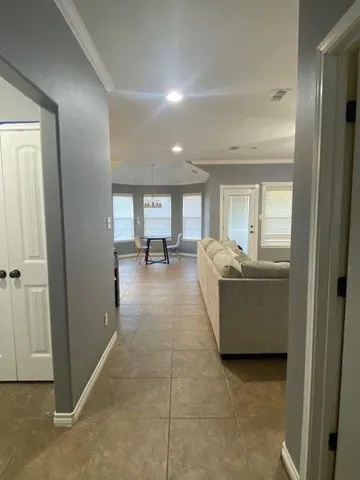 a living room with couches and kitchen view with wooden floor