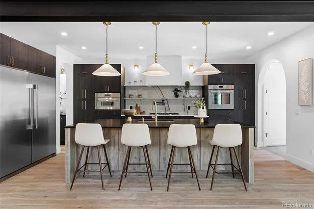 a kitchen with stainless steel appliances kitchen island granite countertop a table chairs and a refrigerator