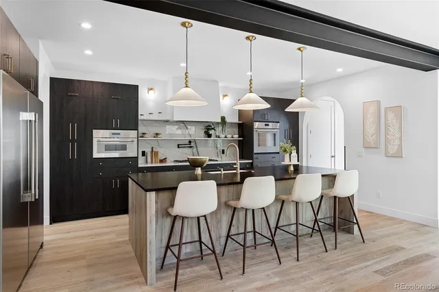 a kitchen with stainless steel appliances kitchen island granite countertop a table chairs and a refrigerator