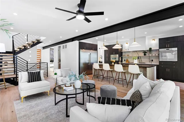 a living room with furniture kitchen view and a wooden floor