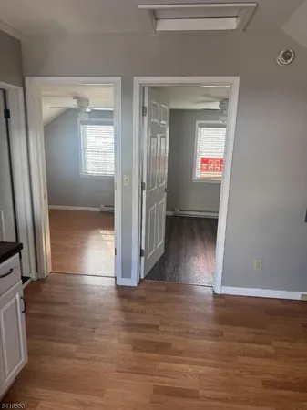 a view of a hallway with wooden floor and a living room