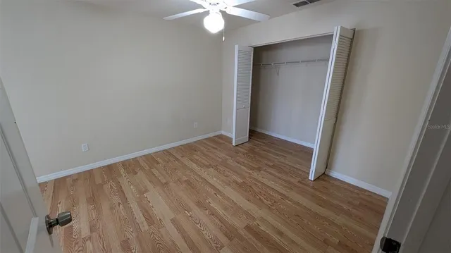 an empty room with a window and a ceiling fan