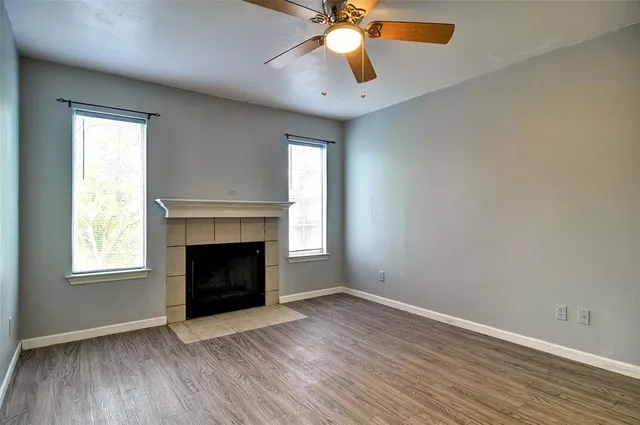 an empty room with windows and fireplace