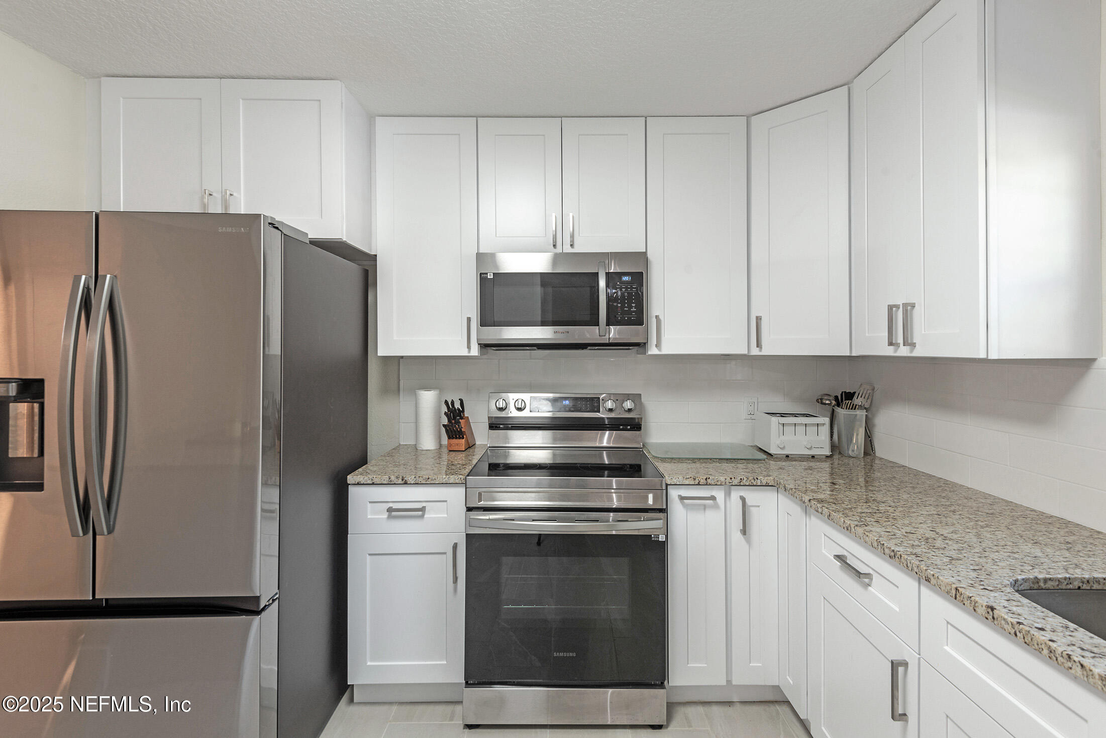 346 Raleigh Road, Unit 346 Jacksonville, FL 32225 - Photo 9 of 43 a kitchen with stainless steel appliances granite countertop white cabinets a refrigerator and a stove