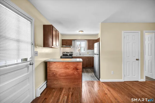 a kitchen with stainless steel appliances granite countertop a refrigerator a sink dishwasher a stove and white countertops with wooden floor