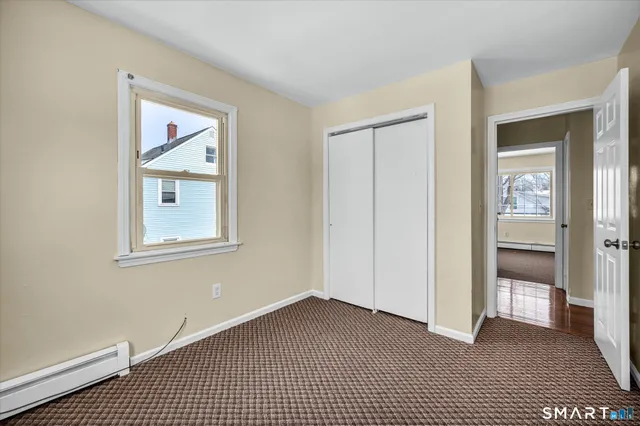 a view of an empty room with closet and a window