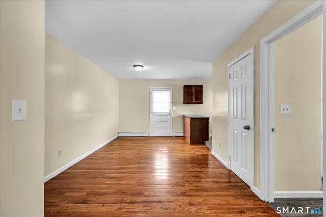 a view of a hallway with wooden floor and a kitchen