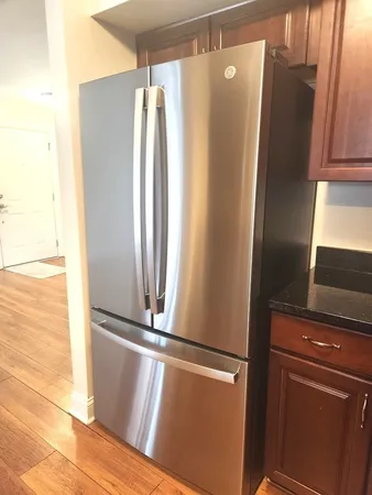 a view of a refrigerator in kitchen and an empty room