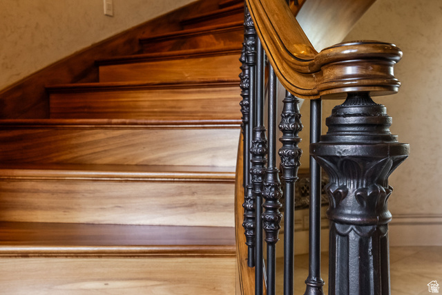 694 West Cephus Road Draper, UT 84020 - Photo 52 of 148 Curved wood-finish staircase featuring a carved newel post and ornate wrought iron balusters with a wood-finish handrail