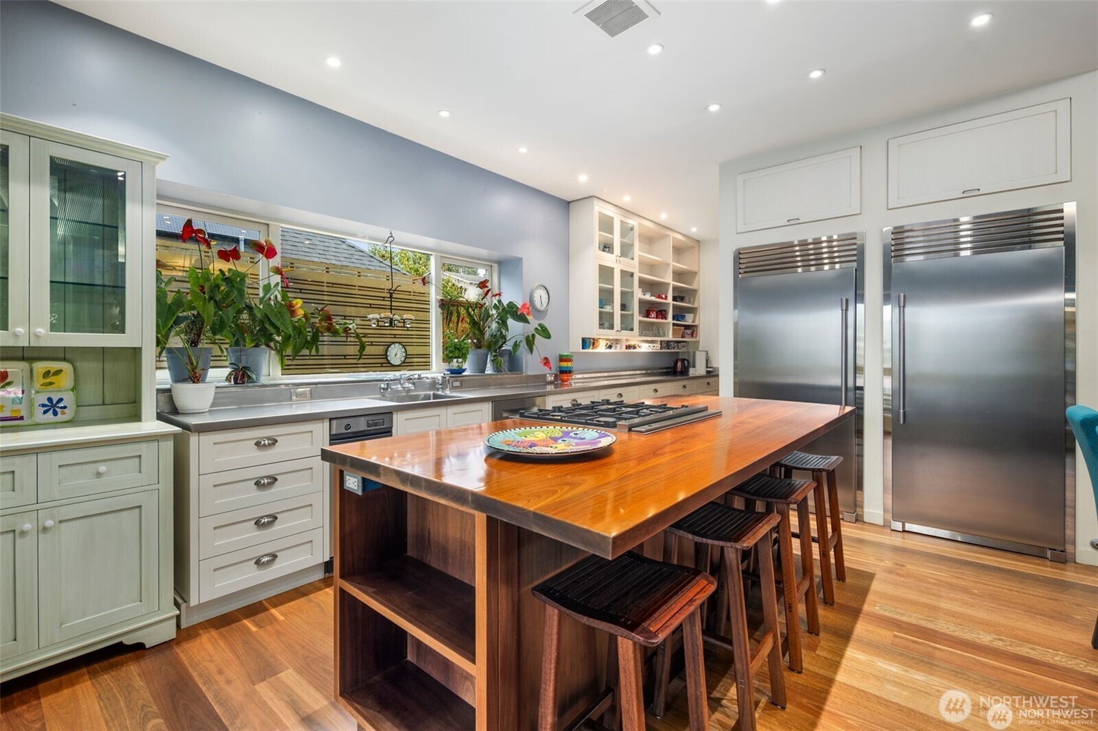 4712 Southwest Brace Point Drive Seattle, WA 98136 - Photo 16 of 40 a kitchen with stainless steel appliances kitchen island granite countertop a table chairs in it and wooden floors