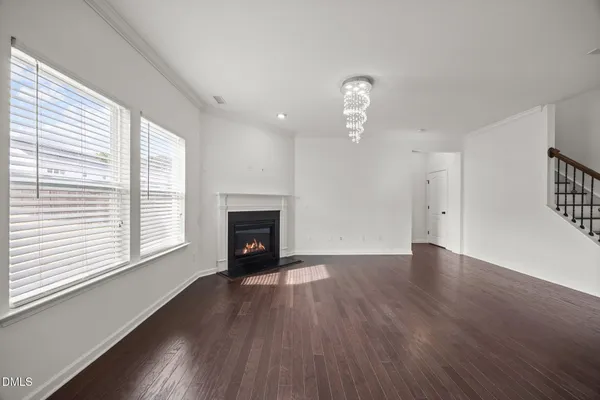 an empty room with wooden floor fireplace and windows