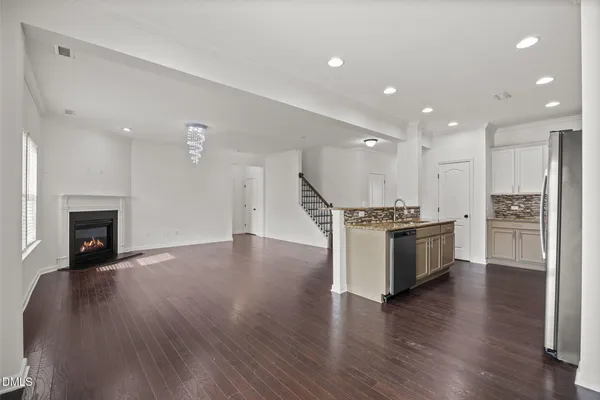 an empty room with wooden floor fireplace and windows