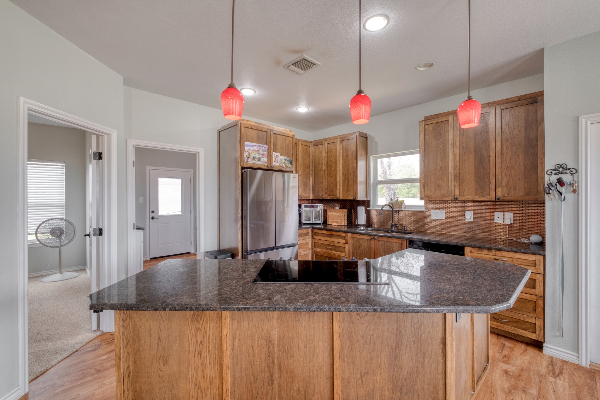 2950 County Road 484 Elgin, TX 78621 - Photo 10 of 25 Kitchen with black appliances, pendant lighting, a kitchen island, light wood-style floors, and tasteful backsplash