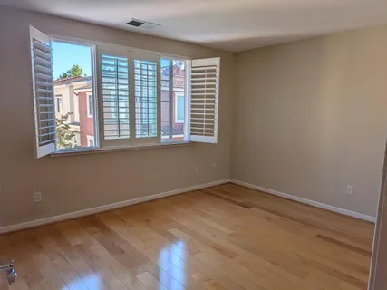 a view of an empty room with wooden floor and a window