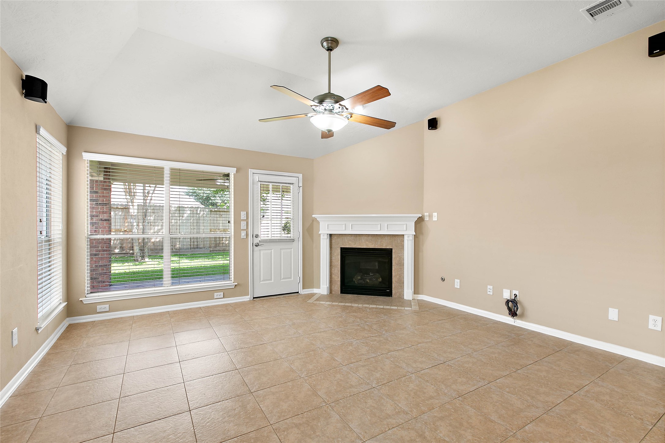 30411 Deleon Fields Drive Spring, TX 77386 - Photo 13 of 24 Cozy living room features a gas log fireplace, speakers for surround sound, and abundant natural light.