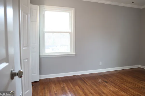 an empty room with wooden floor and windows