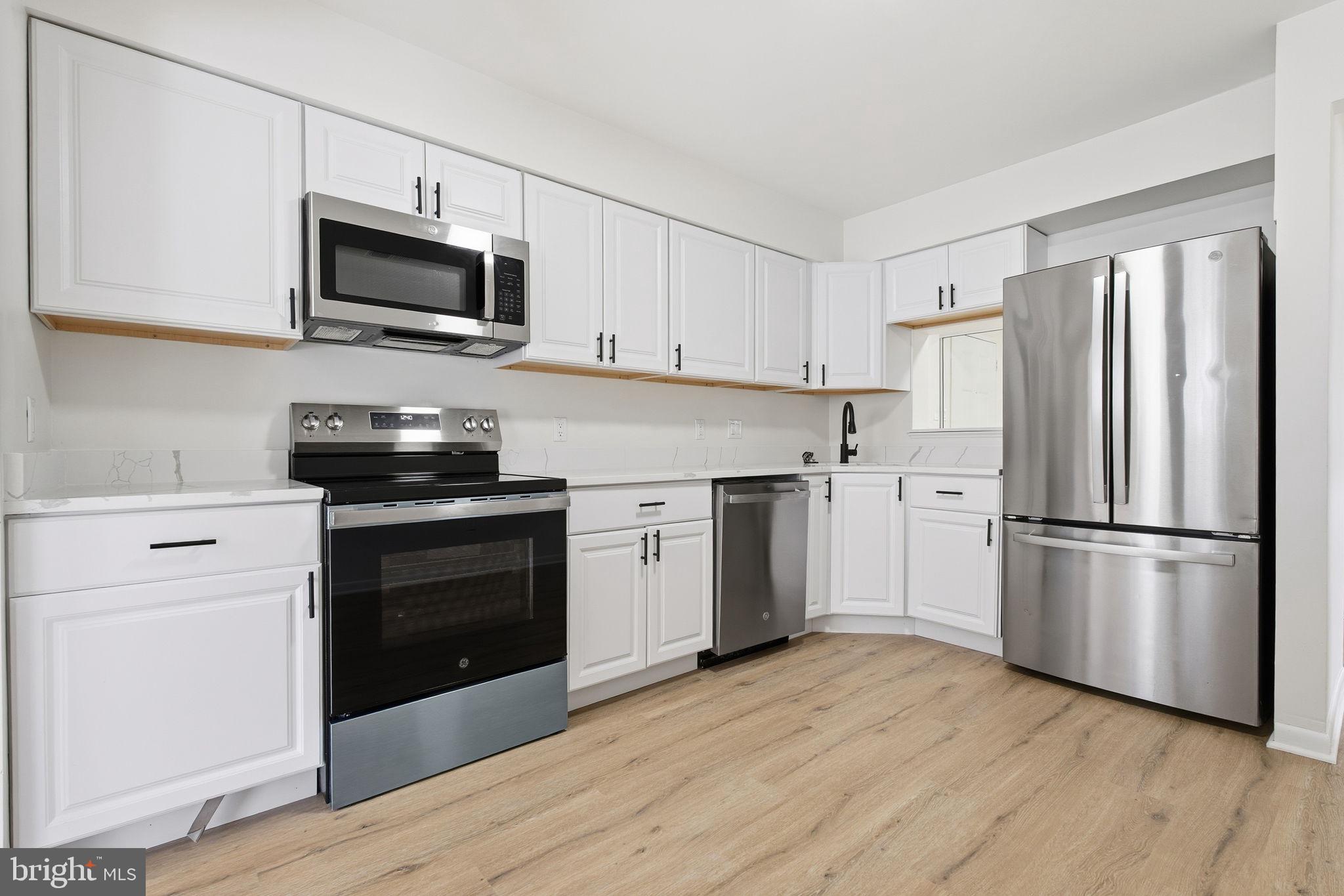 2201 Woodbox Lane, Unit 2201A Baltimore, MD 21209 - Photo 2 of 21 a kitchen with a refrigerator stove and white cabinets