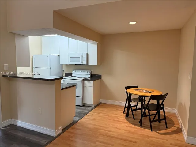 a kitchen with a table chairs a sink dishwasher window and cabinets