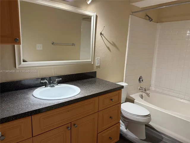 a bathroom with a granite countertop sink toilet a mirror and shower