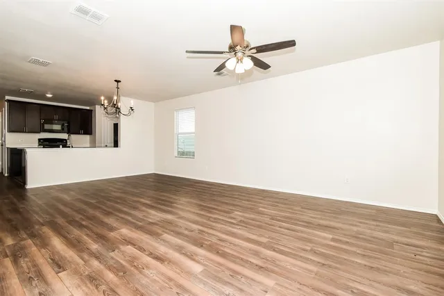 a view of a living room a kitchen and a chandelier fan