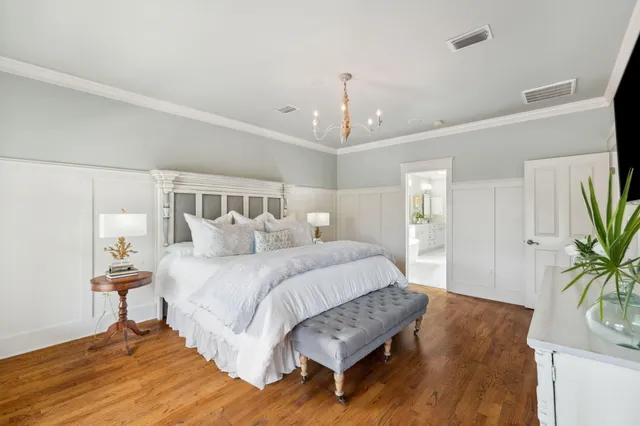 a spacious bedroom with a bed and a potted plant on the dresser