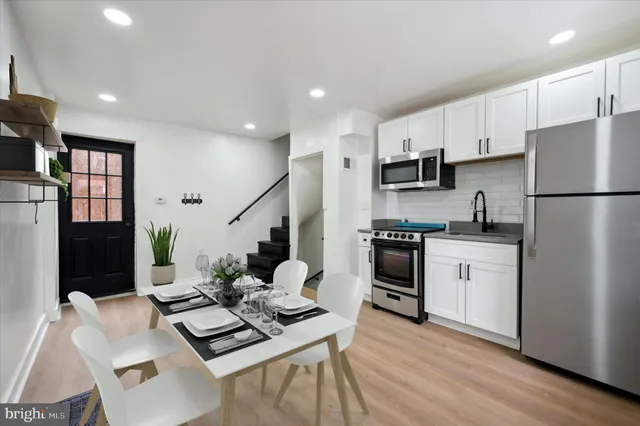 a kitchen with stainless steel appliances white cabinets a refrigerator a stove a sink and a center island