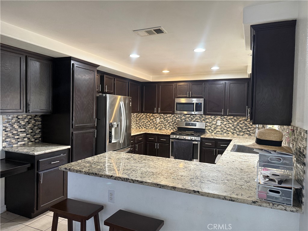 30456 Avenida Caylee Homeland, CA 92548 - Photo 8 of 27 a kitchen with granite countertop stainless steel appliances and wooden cabinets