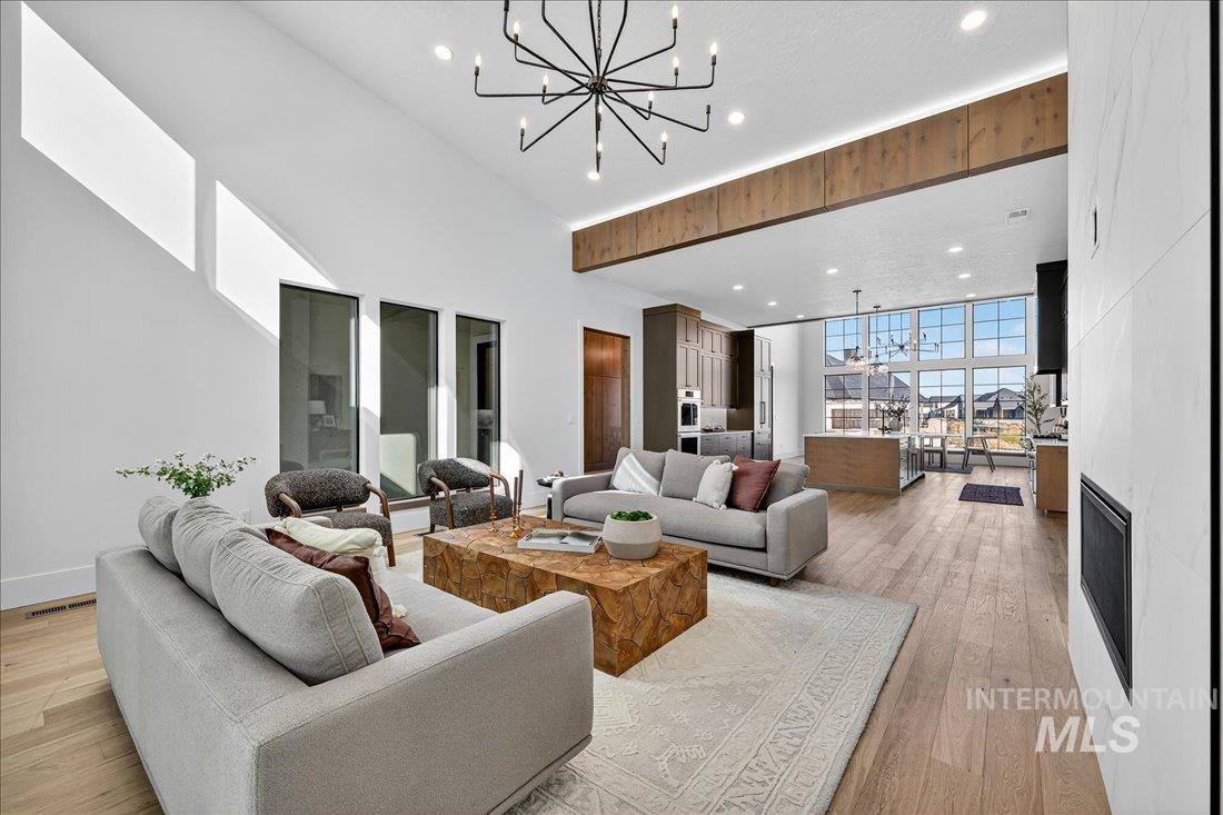 665 Watkins Street Middleton, ID 83644 - Photo 16 of 34 Living area featuring a chandelier, recessed lighting, a large fireplace, light wood-style flooring, and a wall of windows