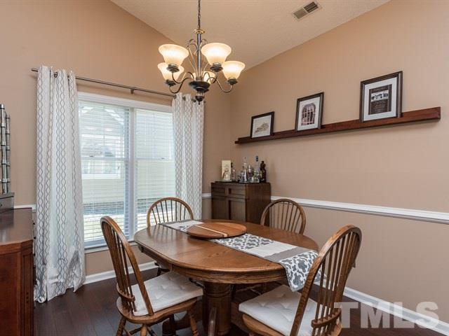 12204 Inglehurst Drive Raleigh, NC 27613 - Photo 3 of 14 a view of a dining room with furniture a chandelier and wooden floor