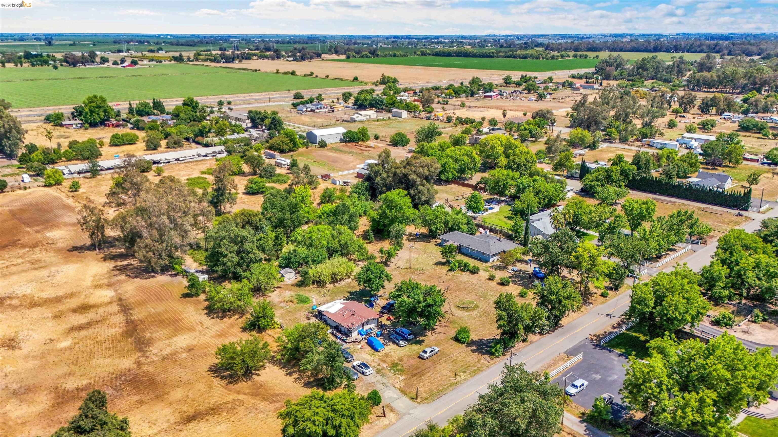 7750 Locke Road Vacaville, CA 95688 - Photo 12 of 23 Expansive parcel featuring a residential structure with a brown roof, mature trees, and a paved road