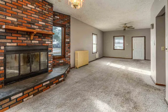 a view of an empty room with a fireplace and window