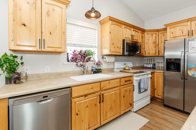972 West 2840th Street South Logan, UT 84321 - Photo 10 of 46 Kitchen featuring light wood cabinetry, stainless steel appliances, light-toned countertops, vaulted ceiling, and wood-finish flooring