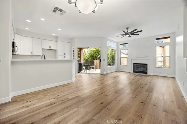 a view of a livingroom with wooden floor a ceiling fan and windows
