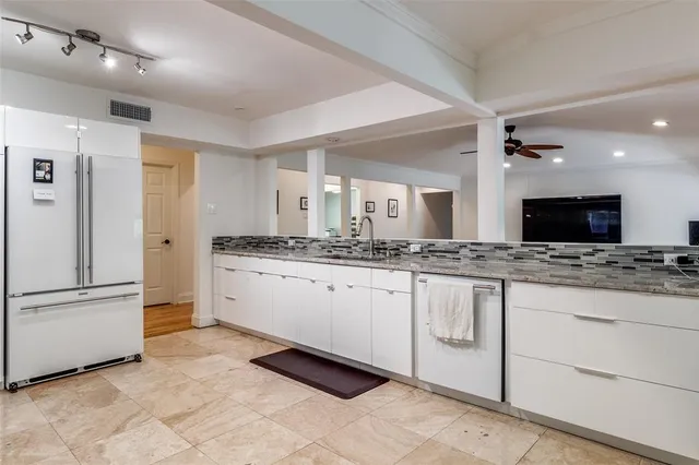 a large white kitchen with a sink and stainless steel appliances