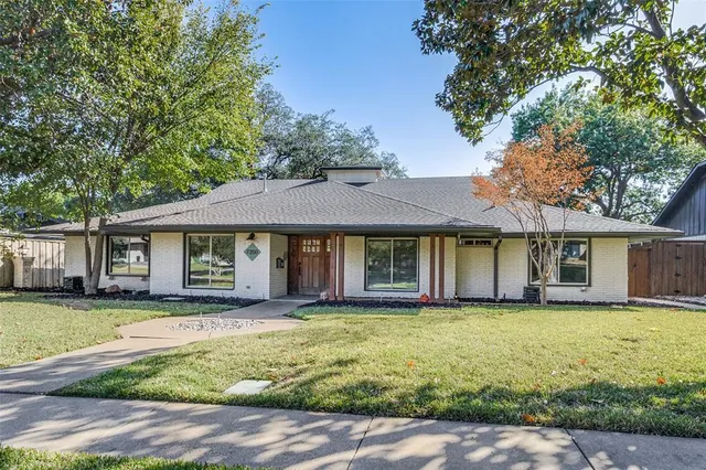 a house that has a big yard with plants and large trees