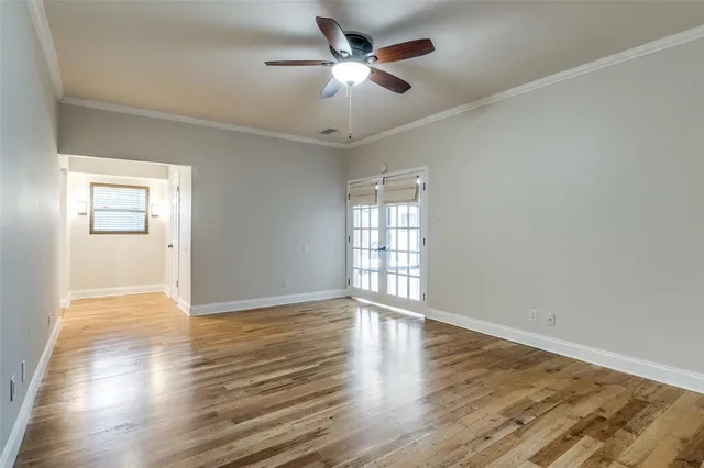 an empty room with wooden floor chandelier fan and windows
