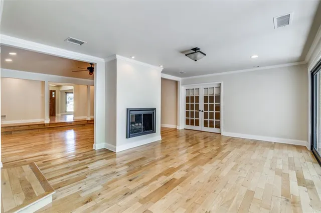 a view of an empty room with wooden floor fireplace and a window