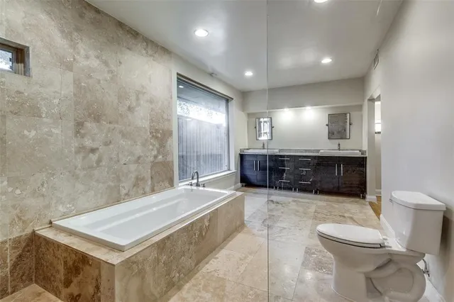 a spacious bathroom with a granite countertop sink a toilet and mirror