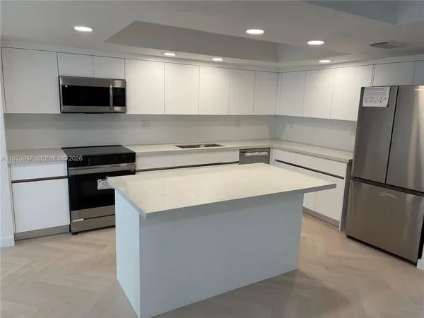 a kitchen with a sink a microwave a refrigerator and cabinets