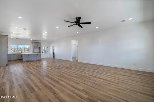 an empty room with wooden floor and ceiling fan