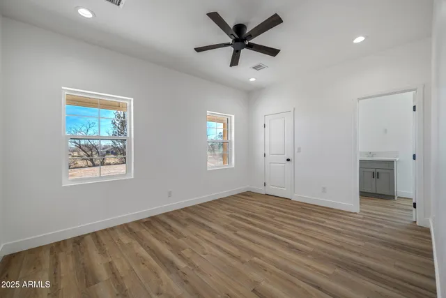 an empty room with a ceiling fan and wooden floor
