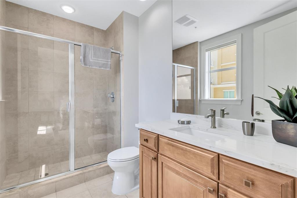 140 Riviera Dunes Way, Unit 1203 Palmetto, FL 34221 - Photo 18 of 30 a bathroom with a shower sink vanity mirror and toilet
