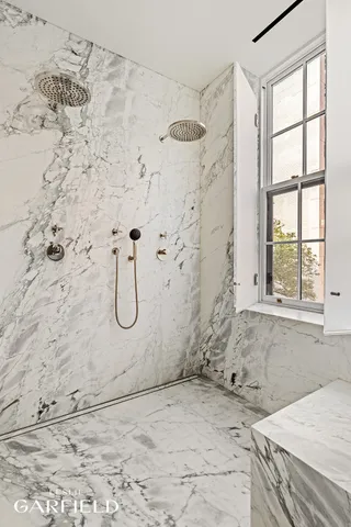 a bathroom with a white bath tub a shower and a window