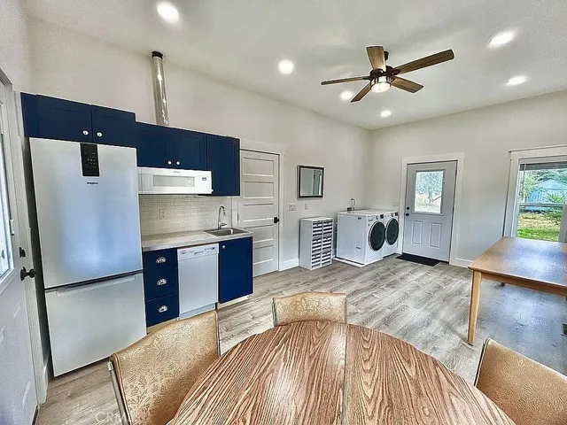 a kitchen with stainless steel appliances granite countertop a refrigerator a sink dishwasher a stove with white cabinets and wooden floor