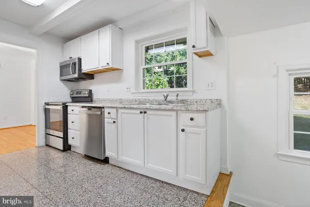a kitchen with white cabinets and window