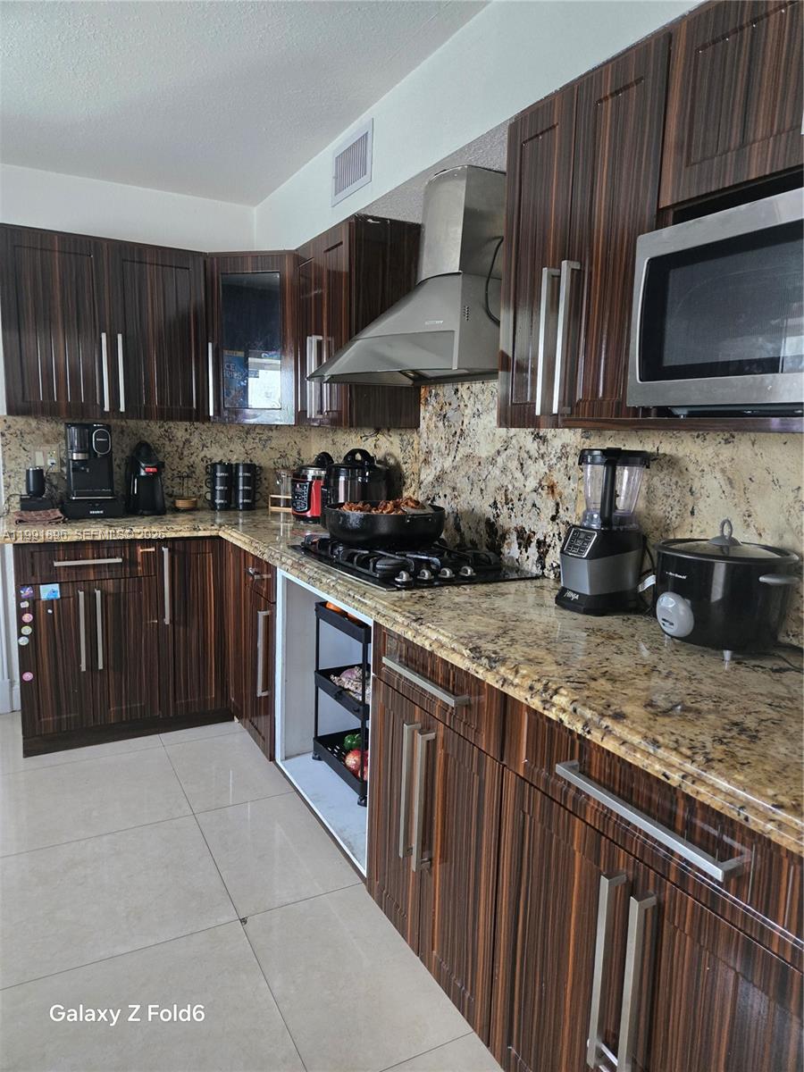 234 East 44th Street Hialeah, FL 33013 - Photo 5 of 14 a kitchen with stainless steel appliances granite countertop wooden cabinets a stove top oven a sink and dishwasher