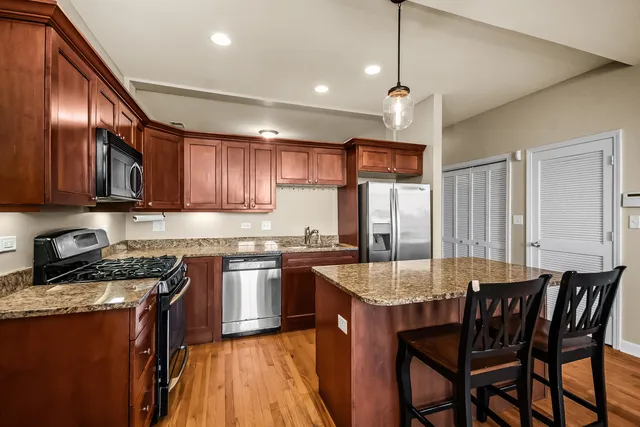 a kitchen with granite countertop stainless steel appliances a table chairs refrigerator and microwave